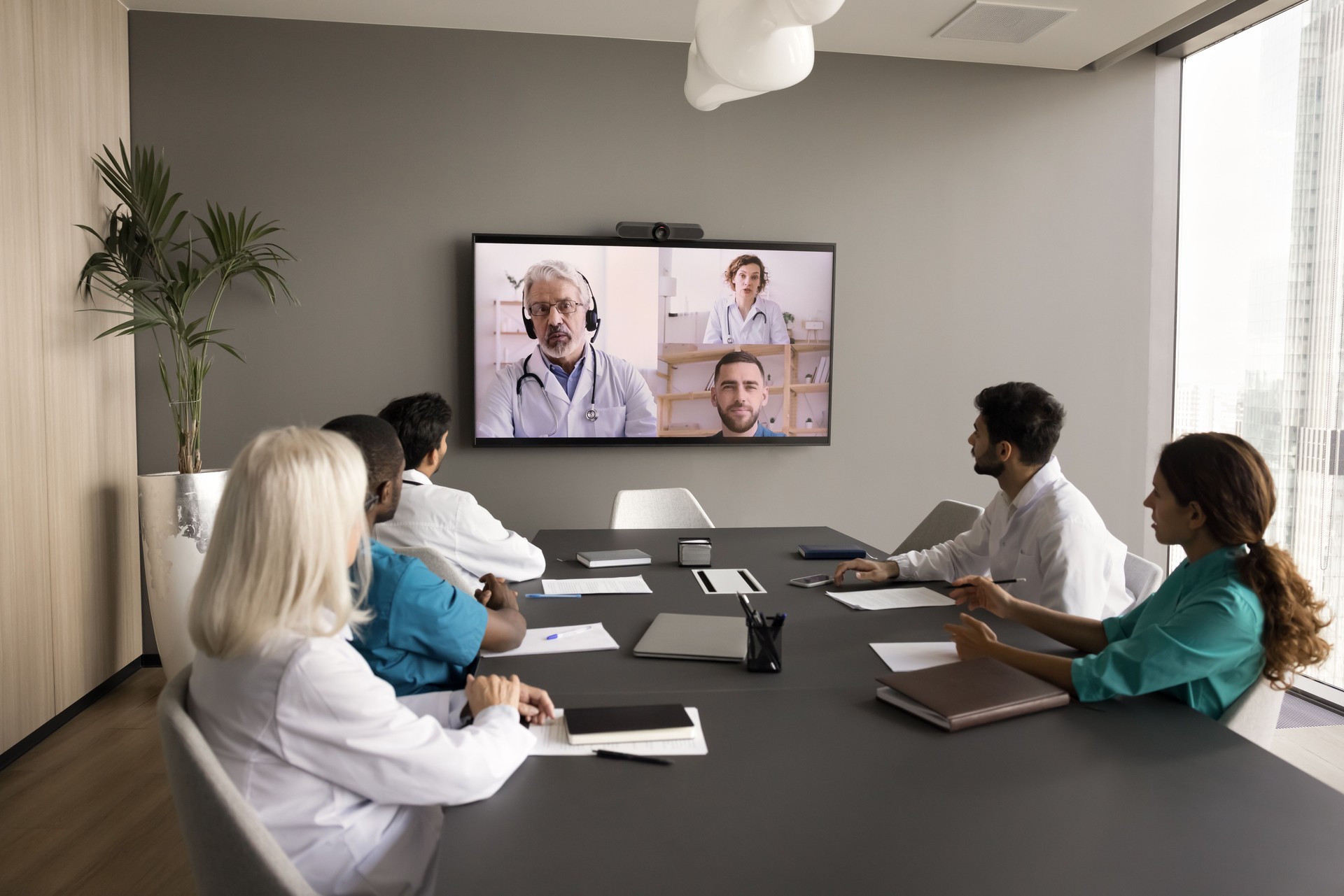 Clinic staff meeting in boardroom, talking to remote medical colleagues